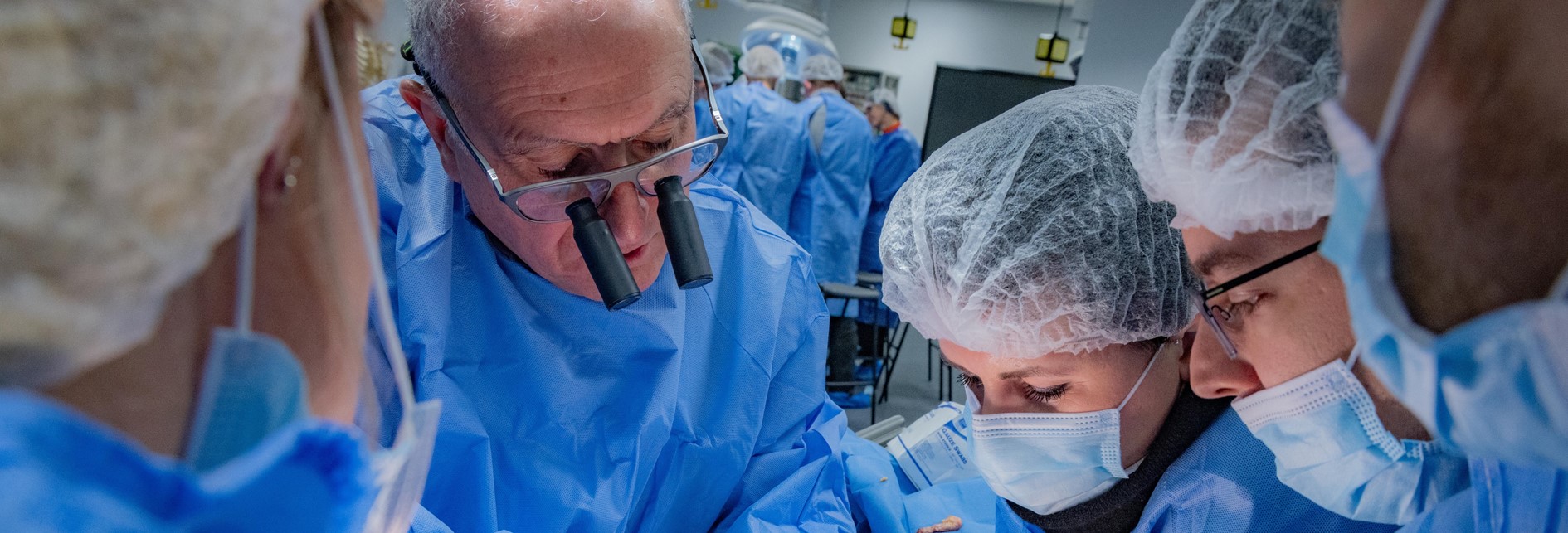 a team of surgeons in blue scrubs looking at something off camera